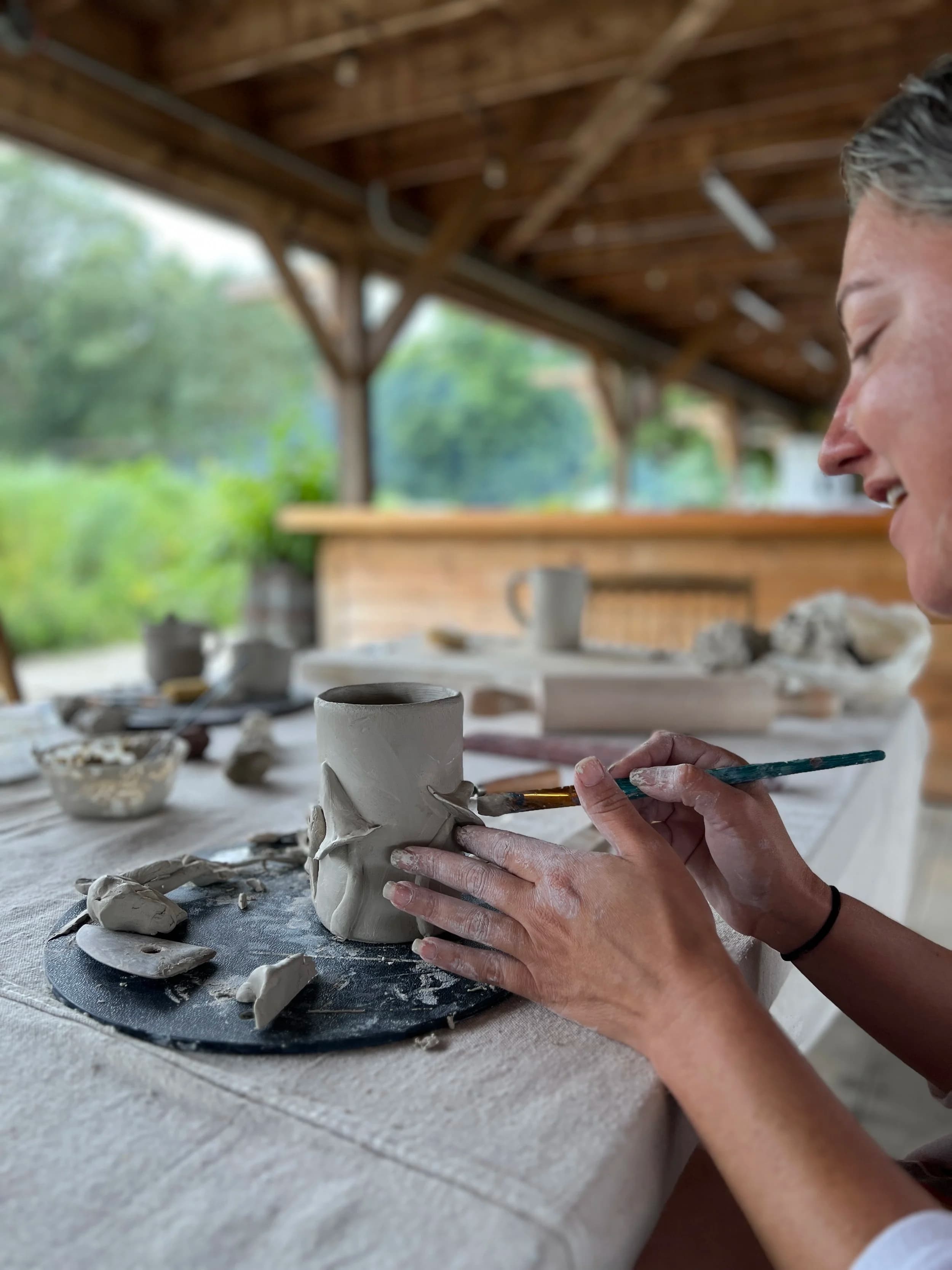 A guest painting a ceramic mug at a pottery workshop