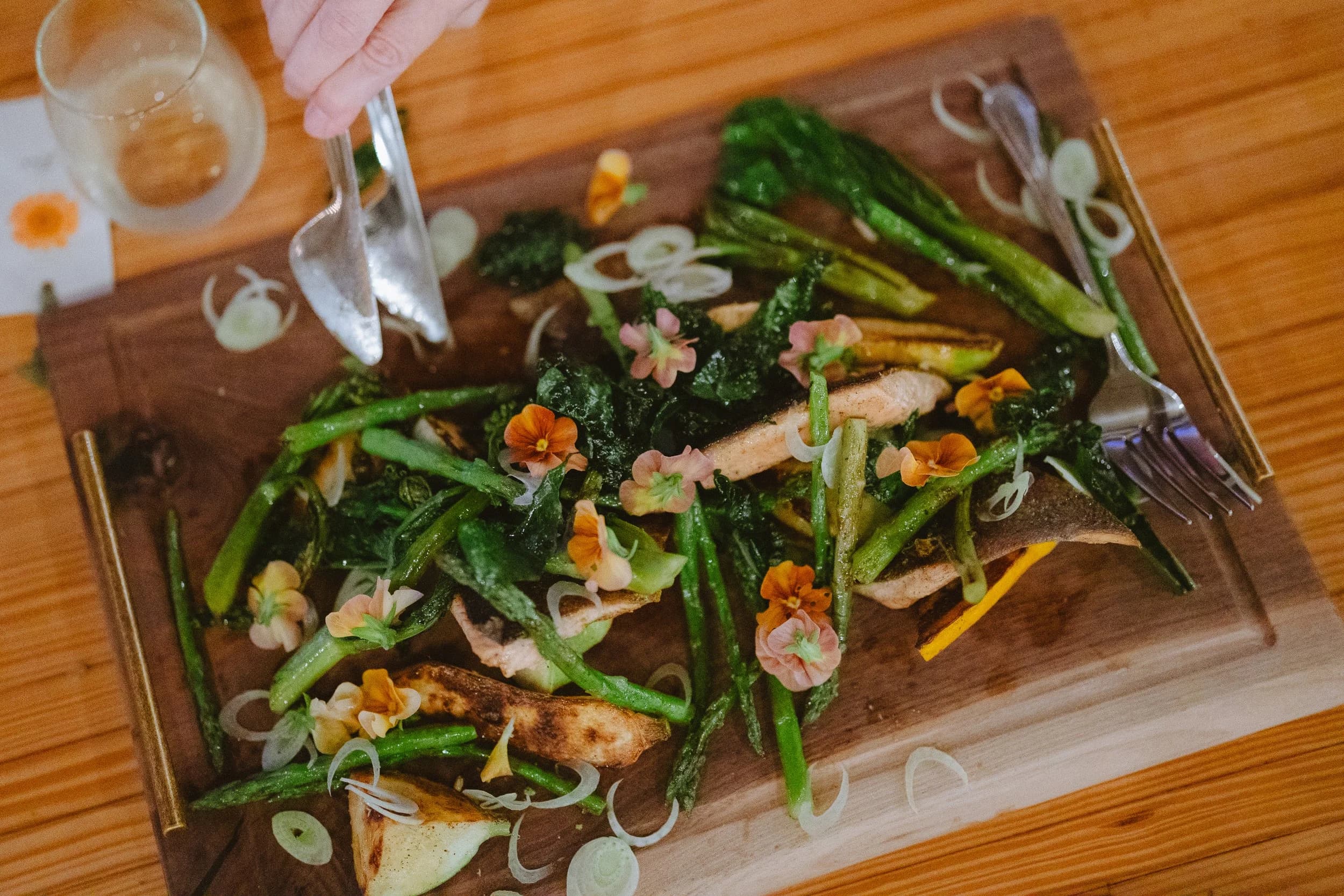 A plated fish dish with greens and edible flowers at a Celeste Dinner Experience