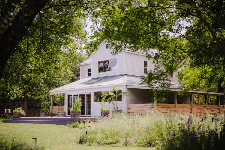 The Celeste Farms farmhouse framed by trees and wildflowers
