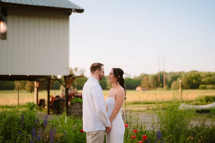 Couple in front of the white farmhouse at sunset